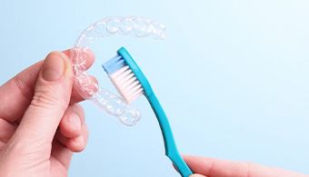 Close up of person brushing their Invisalign tray