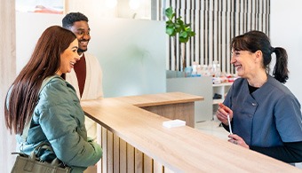 Dental receptionist talking to smiling couple