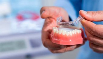 Dentist lifting an Invisalign tray off a dental model