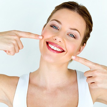 Woman pointing to smile after dental care
