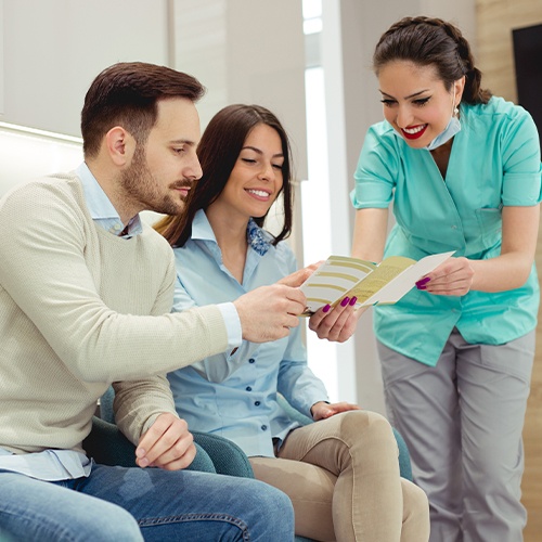 Dental team member discussing treatment options with two dental patients