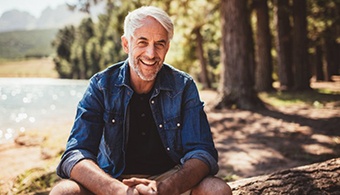 a man smiling while sitting outdoors