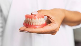 Dentist holding full dentures in Jacksonville