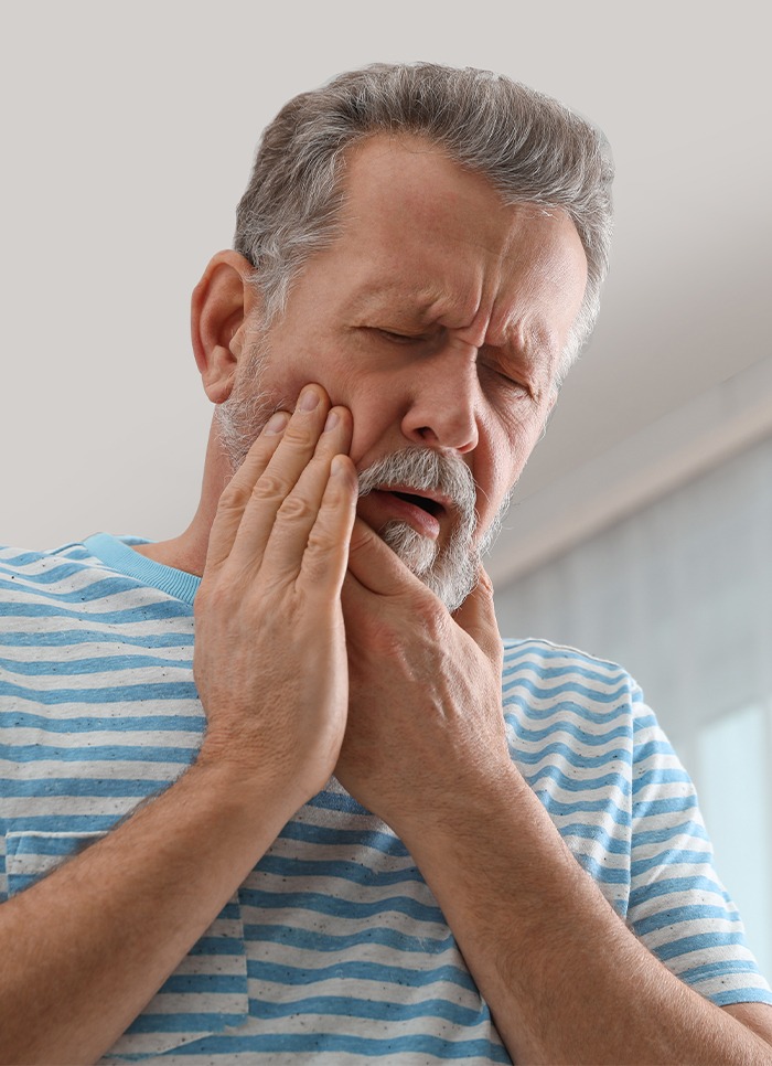 Man in need of emergency dentistry holding cheek