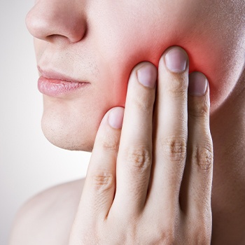 Patient in need of emergency dentistry holding cheek