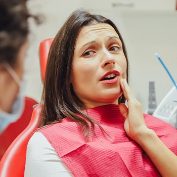 Woman in need of emergency dentistry holding cheek