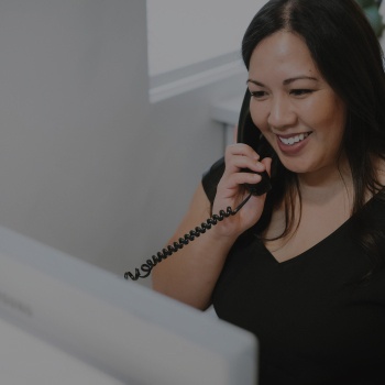 Dental team member sitting at desk and talking on phone