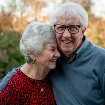 Smiling senior man and woman holding each other outdoors