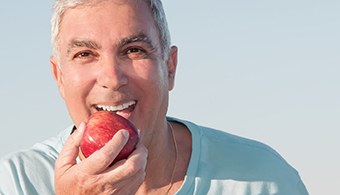 Man with dental implants in Jacksonville, FL eating an apple