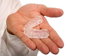 Hand holding a single mouthguard to protect from grinding