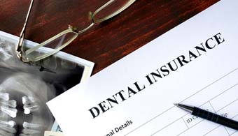 a dental insurance claim form sitting on top of a dental X-ray and money