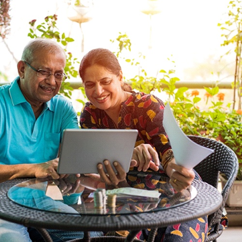 An older couple sitting outside on their patio while talking with someone on their tablet in Jacksonville