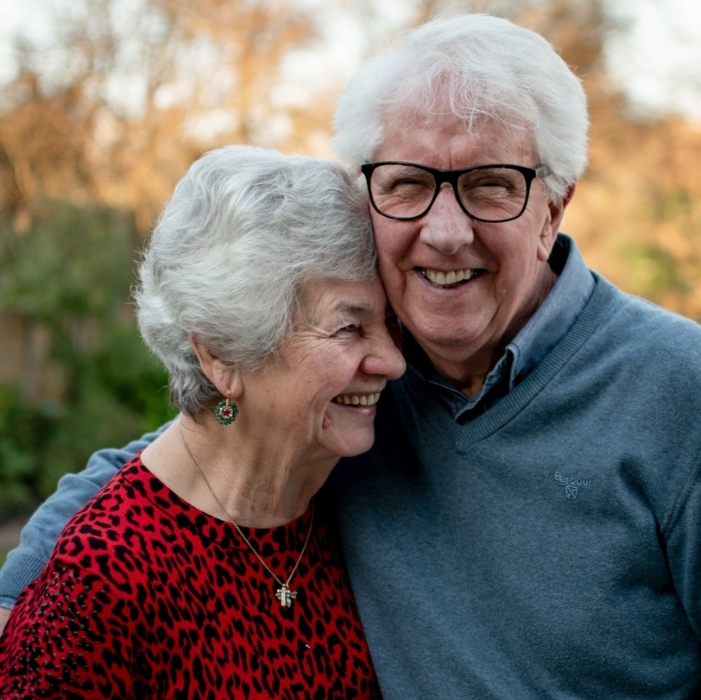 Smiling senior man and woman holding each other outdoors