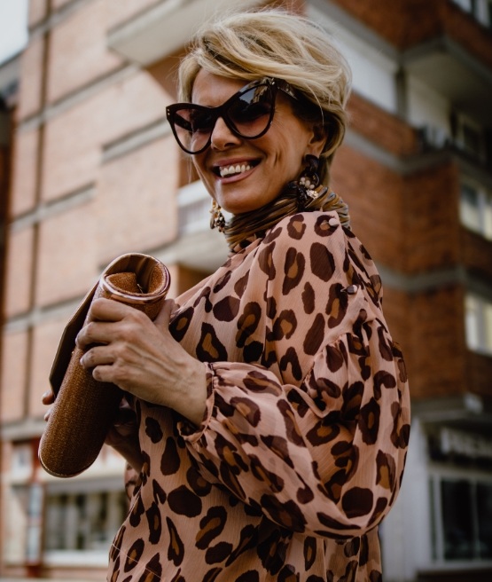 Smiling woman in sunglasses and leopard print blouse