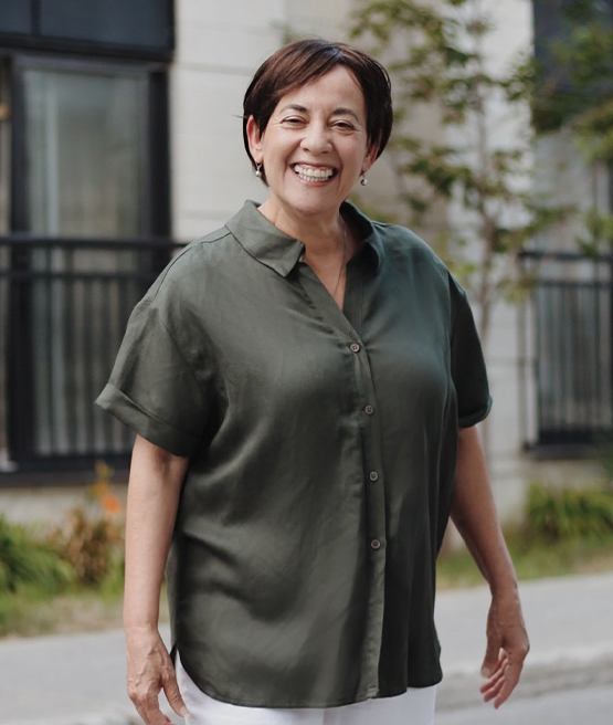 Woman in dark green shirt smiling outdoors