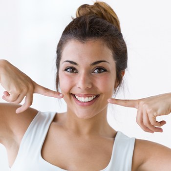 Woman pointing to her smile after preventive dentistry