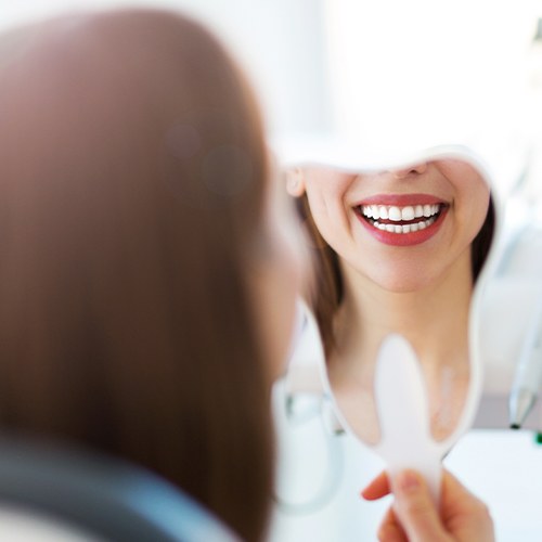 Woman looking at healthy smile during fluoride treatment