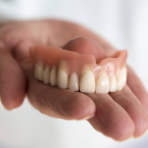 Hand holding dentures