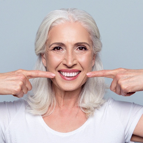 senior woman pointing to her smile