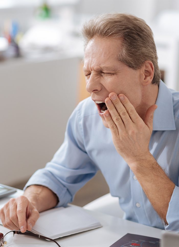 Man in need of T M J therapy holding jaw