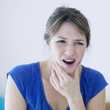 Woman in need of T M J therapy holding jaw