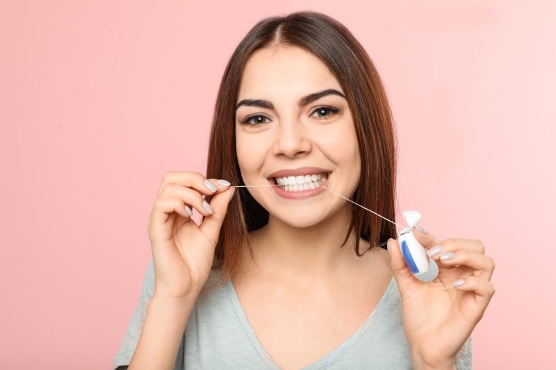 a woman flossing dental implants in Jacksonville