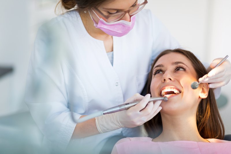 Woman smiles receiving dental care.