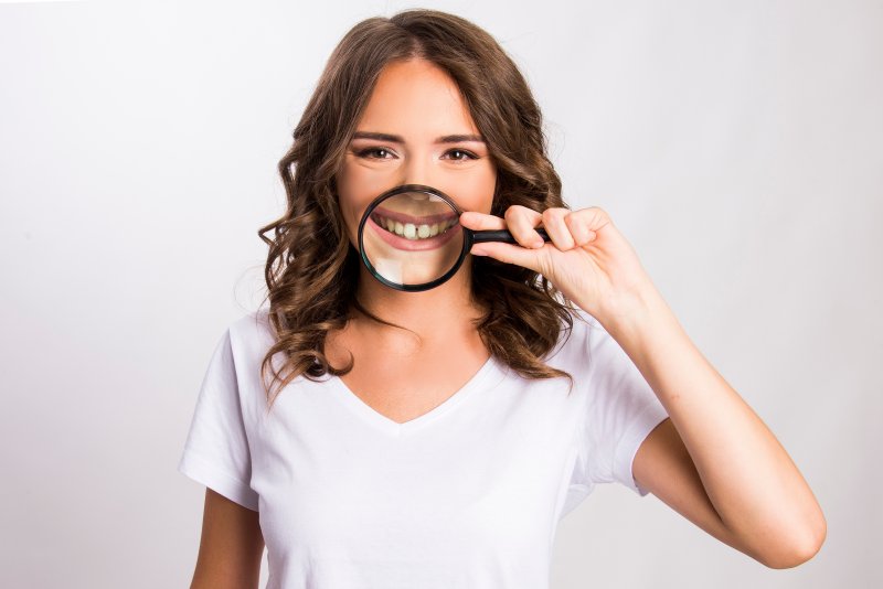 A girl holding a magnifying glass up to her diastema