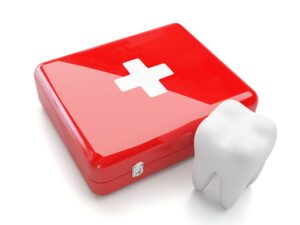 Large fake tooth next to a shiny red emergency kit