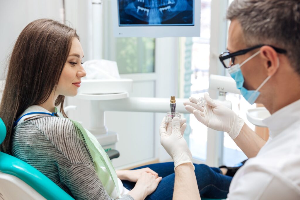 Dentist showing sample implant to patient