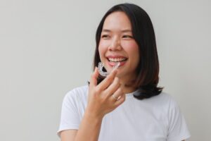 Woman putting in her Invisalign tray after brushing her teeth