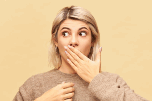 Woman covering her mouth after losing her dental crown