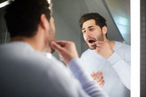 Man examining his teeth in the mirror.