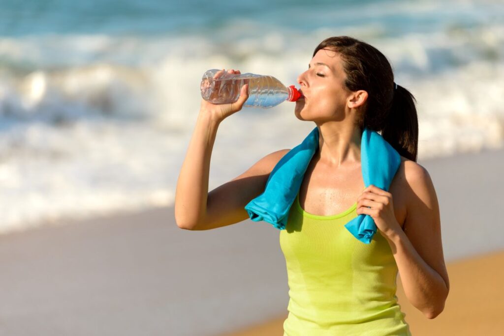 A woman on the beach drinking water