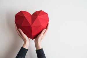 Hands holding up origami heart to represent heart health